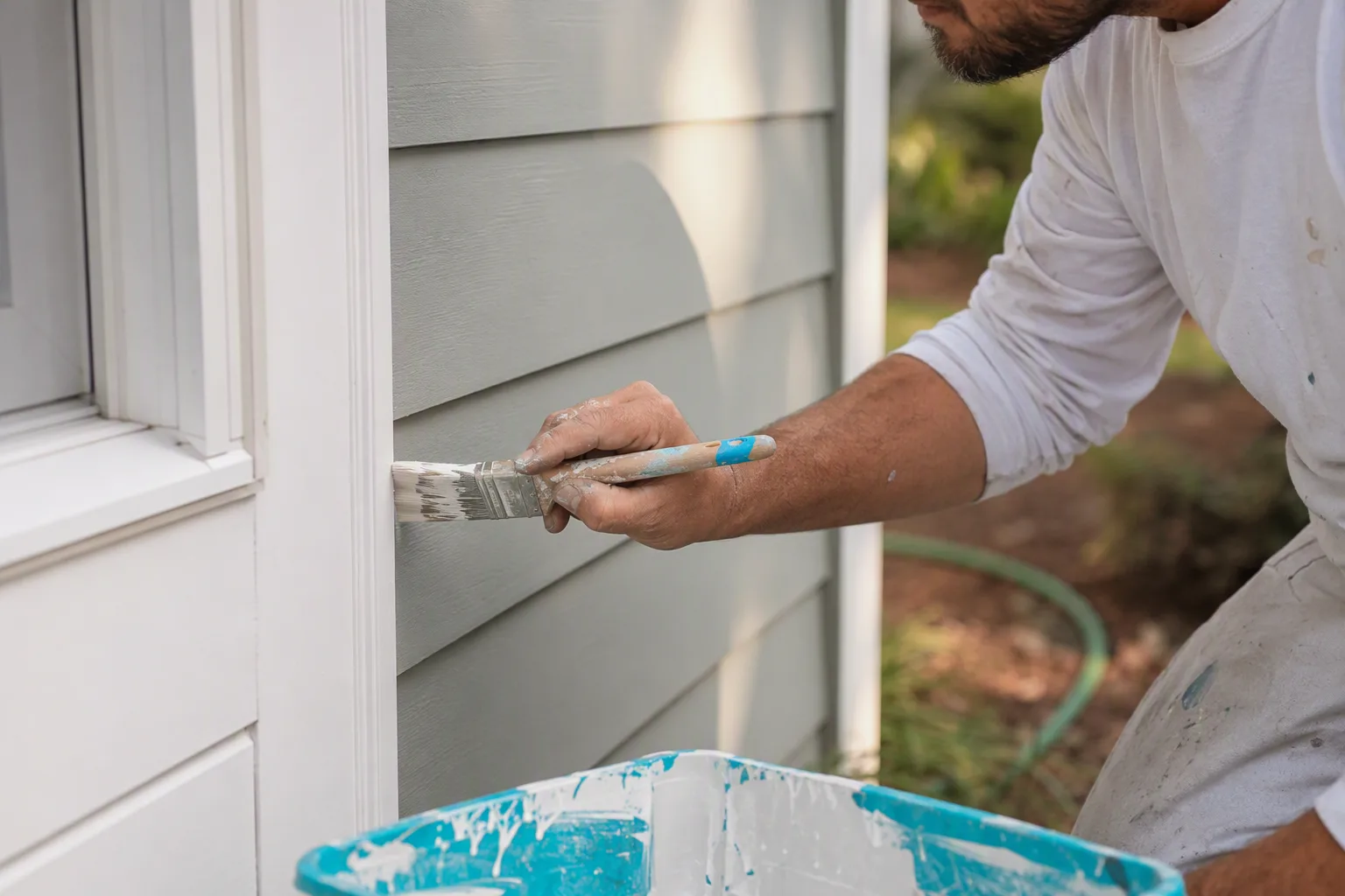 A house painter cutting in a clean line where a wall meets white trim